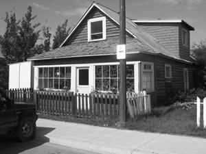 Captain Coglin House is a 1-1/2 storey log house with a gable roof sheathed with corrugated metal roofing. The front has a porch with a hip roof and the east facade has a frame shed dormer.