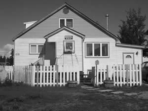 The Greenough House is a 1-1/2 storey frame residence has a gabled roof and gabled entry. An approximate dimension is 30′ by 33′. Ship lap wood siding covers the exterior and the foundation is concrete with a basement. 