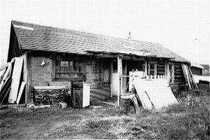 The Pioneer Hotel is a one-storey log structure with a gable roof and a frame false facade. The foundation is a log sill construction. Roll asphalt covers both the roof and exterior siding. 