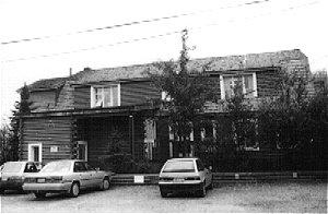 The TC Richards Building has a squared log construction with a gambrel roof and shed dormers. The structure rests on a concrete foundation.
