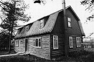 The Taylor House is a log structure has a bell cast gambrel roof and shed dormers. There is a timber frame grade beam. Wood shingles are on the roof and exterior siding.