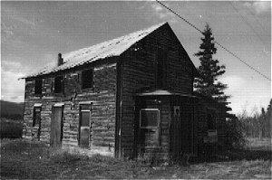 Whitney Black Silver Fox Farm is a two-storey log structure with a gable roof. A partial dirt basement lies within a log sill foundation. Corrugated metal covers the roof.