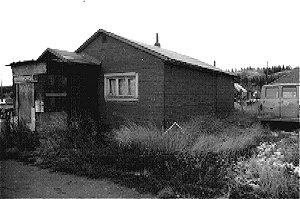 The Eldon House is a one-storey wood frame building with a gable roof. Asphalt shingle roofing covers the roof and the walls are covered with roll asphalt siding. The foundation is a wood sill construction.