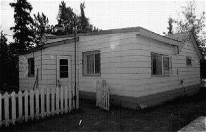 The original log structure had gable and shed roofs and a L-shaped floor plan. Asphalt shingles covered the roof and the exterior is covered by aluminium siding. There are wood frame additions to both the west and north sides of building.